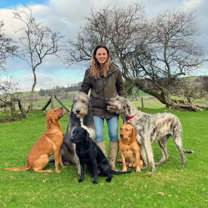 Emily standing in a Welsh field with five dogs sitting around her