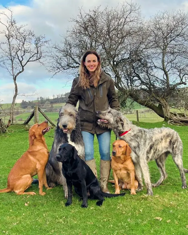 Emily standing in a Welsh field with five dogs sitting around her